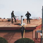 Two people on a roof inspecting a repair in progress